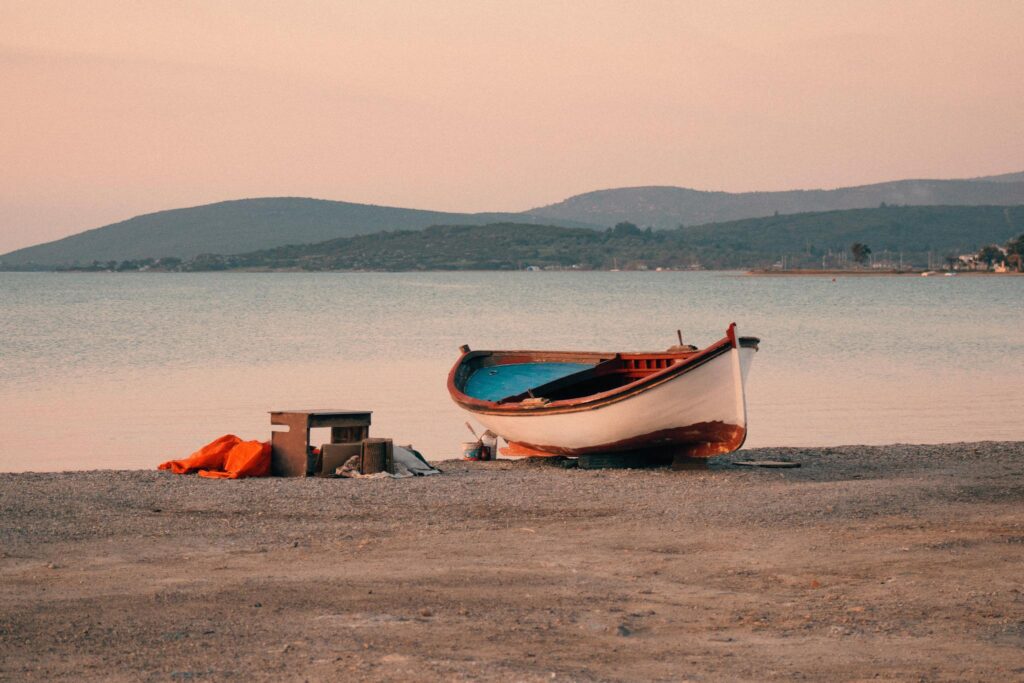 A serene boat scene on Urla's beach in İzmir, Türkiye during a calm sunset moment.